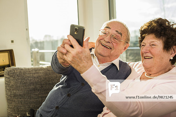 Senior couple taking a selfie with smartphone at home