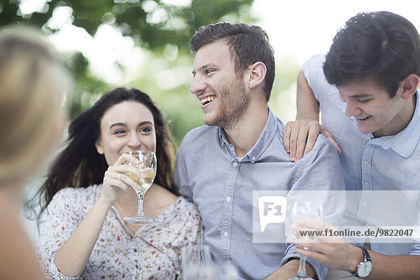 Happy friends drinking wine outdoors