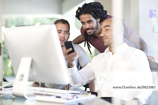 Man showing co-workers something on his phone