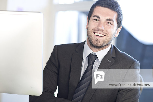 Portrait of smiling young businessman at desk in an office