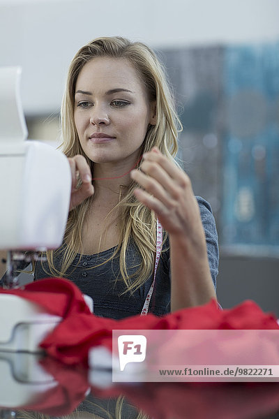 Junge Frau  die mit einer Nähmaschine arbeitet