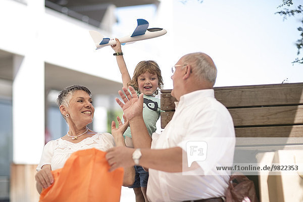 Großvater und Großmutter schenken Enkel ein Spielzeugflugzeug