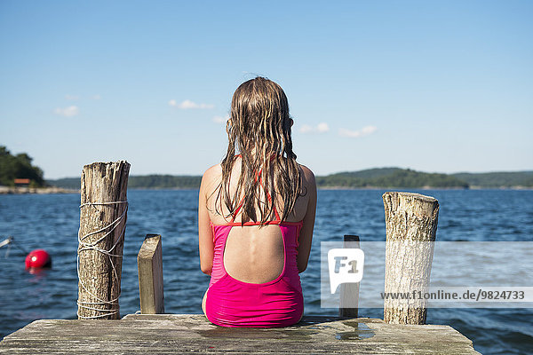 Girl sitting on jetty and looking at sea