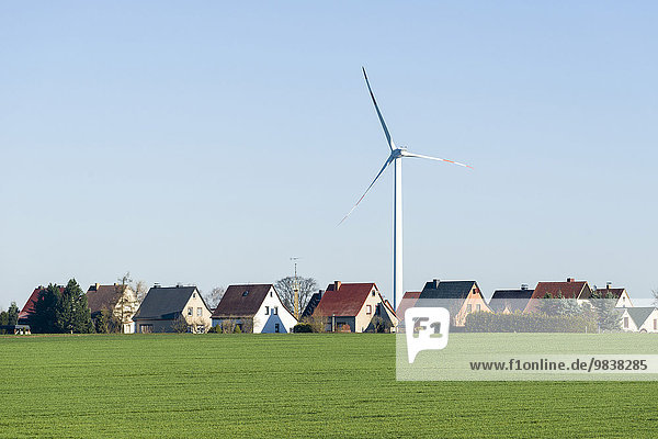 Windkraftanlage an einem Dorf mit Häusern in einer Agrarlandschaft  Räckelwitz  Sachsen  Deutschland  Europa