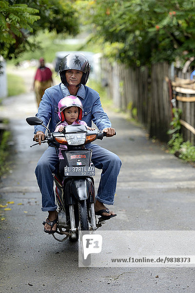 Man with child on a motorcycle  Gampong Nusa village  Aceh  Indonesia  Asia