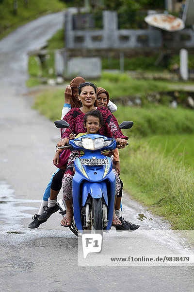 Woman with three girls on a motorcycle  village Gampong Nusa  Aceh  Indonesia  Asia