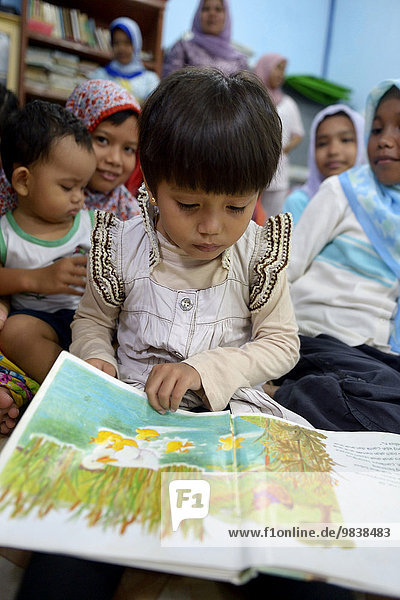 Girl looking at a picture book  Gampong Nusa village  Aceh  Indonesia  Asia
