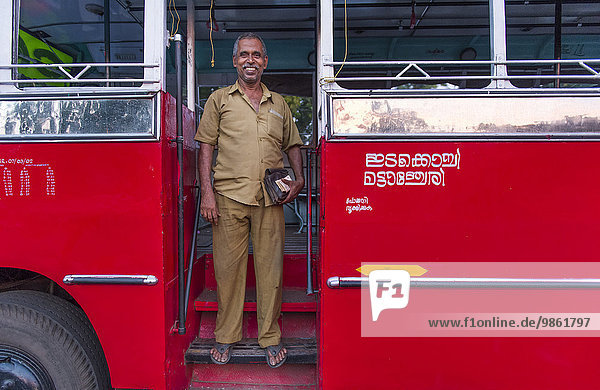 Busfahrer vor rotem Bus  Kerala  Indien  Asien