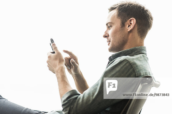 Ein Mann sitzt und überprüft sein Telefon.
