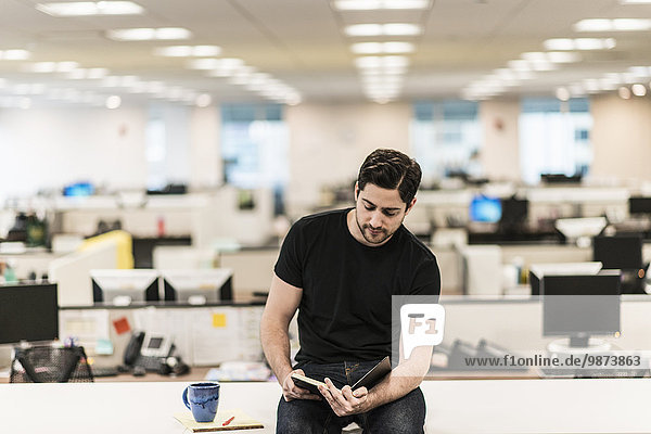 Ein Mann  der auf einem Schreibtisch in einem Büro sitzt und sich ein Buch oder Tagebuch ansieht.