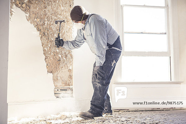 Hispanic construction worker hammering wall