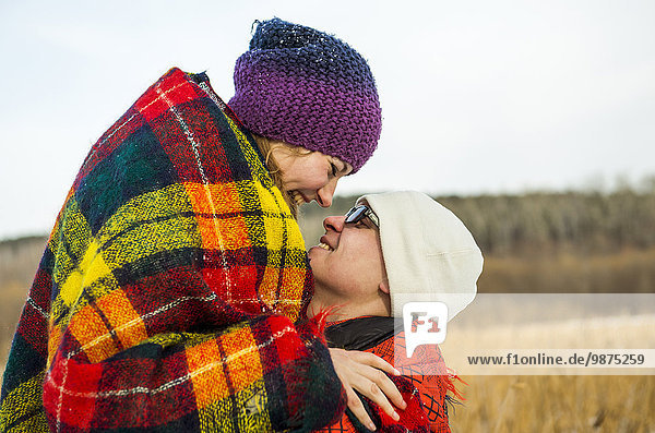 Caucasian couple wrapped in blankets outdoors