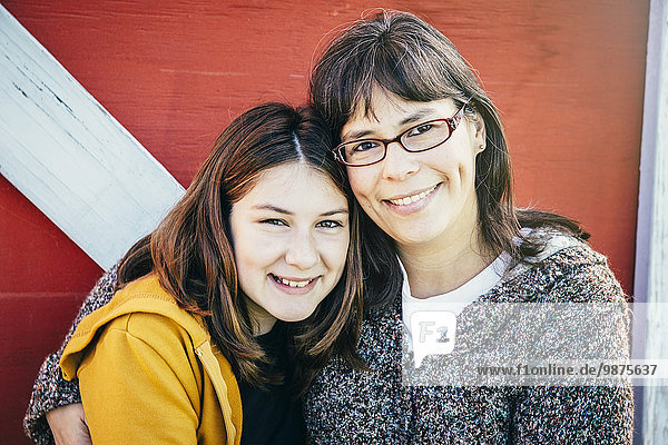 Caucasian mother and daughter smiling outside barn