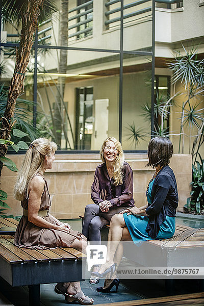 Businesswomen talking in office courtyard