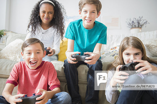 Children playing video games on sofa