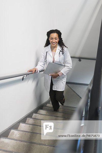 High angle view of mixed race doctor climbing staircase