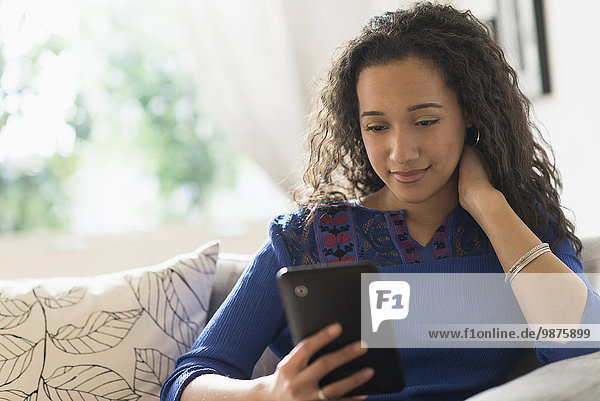 Mixed race woman using digital tablet on sofa