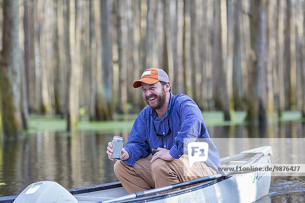 Caucasian man drinking beer in canoe on river