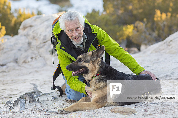 Older man petting dog on rocky hillside