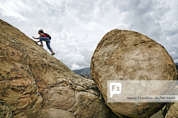 Hispanic woman climbing rocky hillside