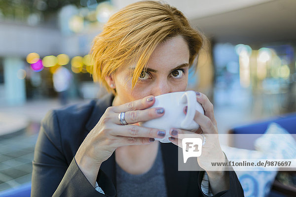 Caucasian businesswoman drinking coffee at sidewalk cafe