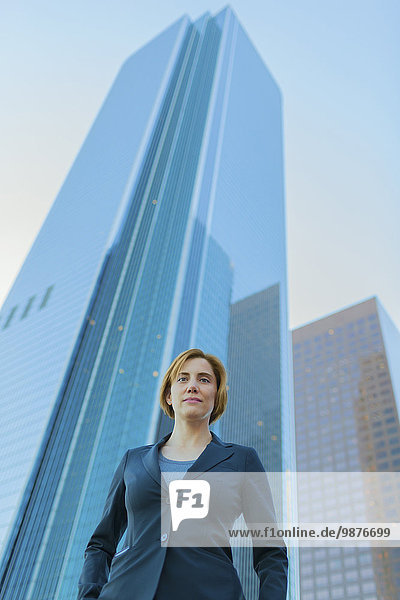 Low angle view of Caucasian businesswoman under high rise buildings
