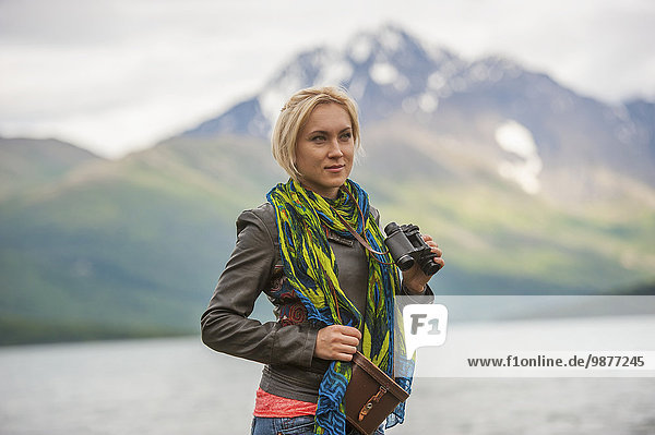 Woman using binoculars at Eklutna Lake  Chugach Mountains  Chugach State Park  Southcentral Alaska