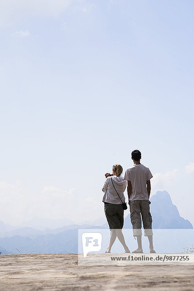 'A couple stands at a lookout with a view over the valley between Luang Prabang and Vang Vieng; Laos'
