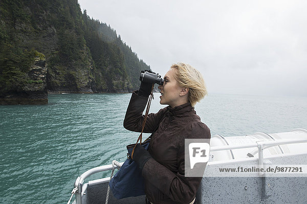 Woman using binoculars to spot wildlife on cruise of Resurrection Bay  Seward  Southcentral Alaska