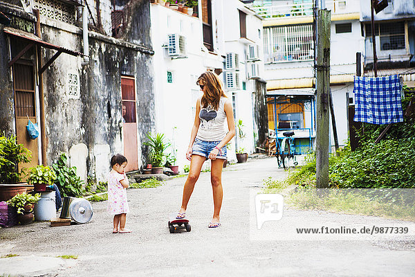 'Young female tourist with a skateboard on a downtown street; Penang  Malaysia'