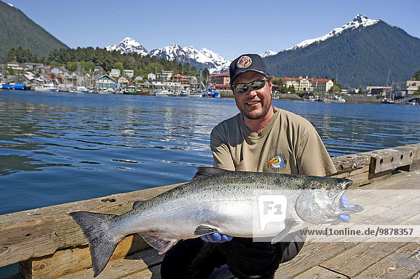 Fisherman Holds Up Chinook Salmon Catch Of The Day On A Dock In Sitka  Alaska