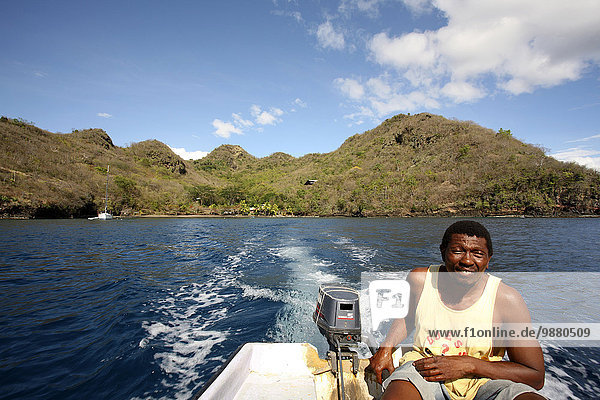 'A man rides in a motorboat at Petit Byahaut; St. Vincent and the Grenadines'