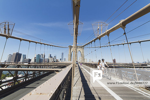 Couple on a tandem bicycle on the pedestrian walkway on the Brooklyn Bridge  New York City  New York  United States