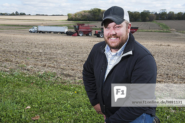 Portrait of a farmer with his farmland and equipment in the background; Minnesota  United States of America