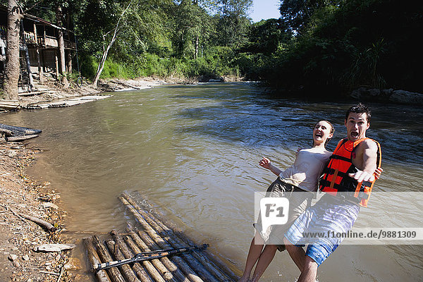 'Young tourists bamboo rafting down the river; Chiang Mai  Thailand'