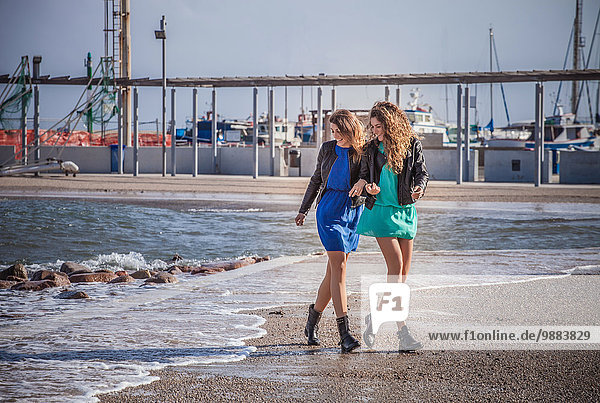 Zwei junge Frauen  die am Strand spazieren gehen.