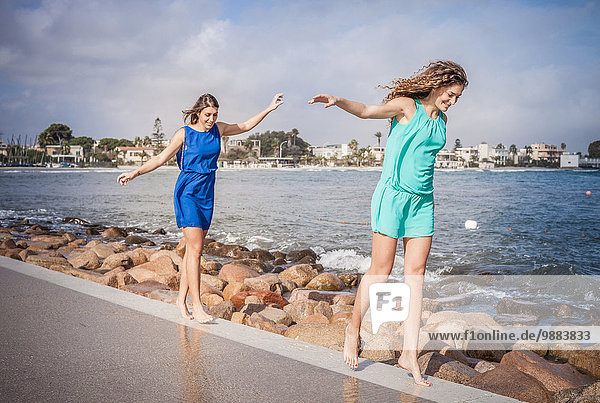 Zwei junge Freundinnen gehen barfuß an der Promenade entlang