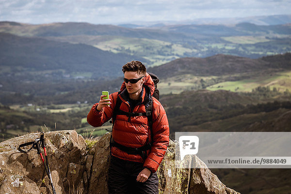 Young male hiker taking smartphone selfie from mountain  The Lake District  Cumbria  UK