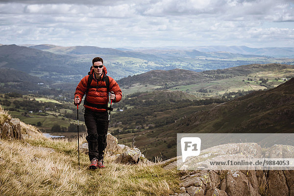 Young male hiker hiking up mountain  The Lake District  Cumbria  UK