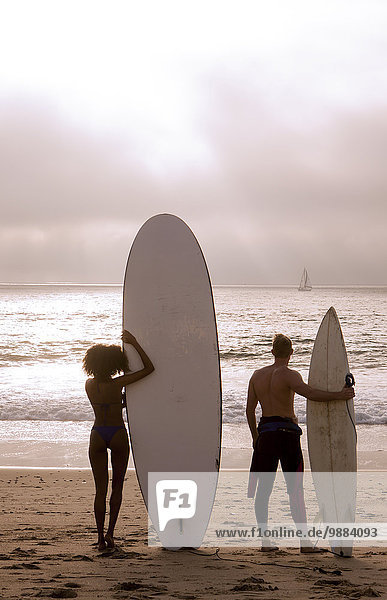 Rear view of young surfing couple looking out to sea  Playa Del Rey  California  USA