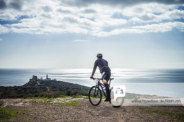 Silhouetted view of male mountain biker on coastal path  Cagliari  Sardinia  Italy