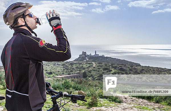 Mittlerer Erwachsener  männlicher Mountainbiker  Trinkwasser auf dem Küstenweg  Cagliari  Sardinien  Italien