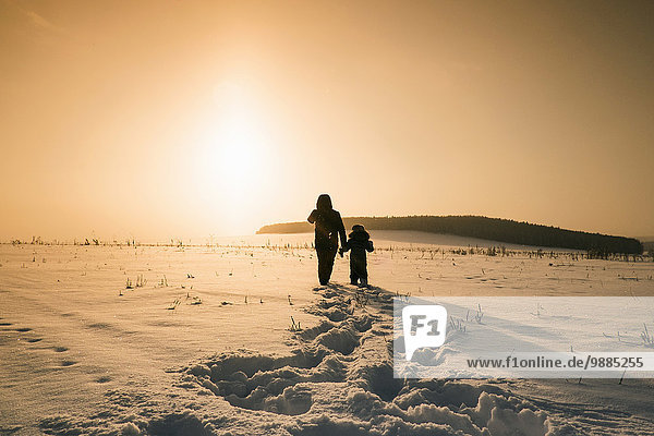 Rückansicht von Mensch und Sohn bei Sonnenuntergang in verschneiter Landschaft Dorf Sarsy Gebiet Swerdlowsk Russland