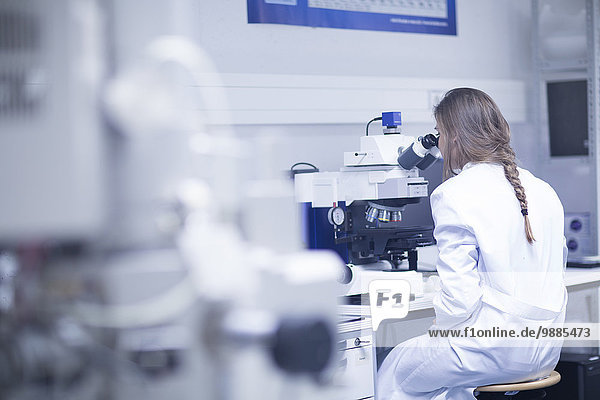 Wissenschaftlerin beim Blick durch das Rasterelektronenmikroskop im Labor