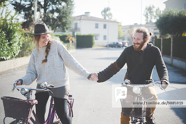 Young couple cycling  holding hands