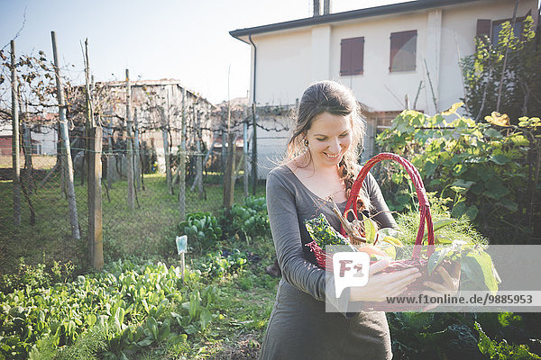 Young woman with basket of homegrown vegetables