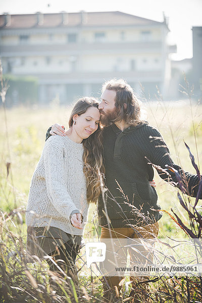 Young couple wearing touching plants in field