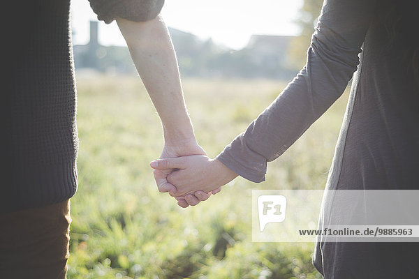 Young couple holding hands in sunlight