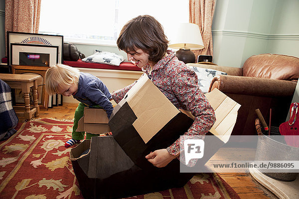 Mother and son playing with cardboard boxes in living room