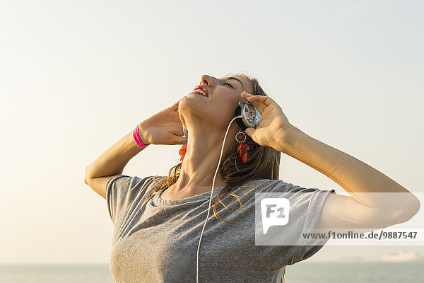 Young woman listening to music with her headphones on the beach; Xiamen  China